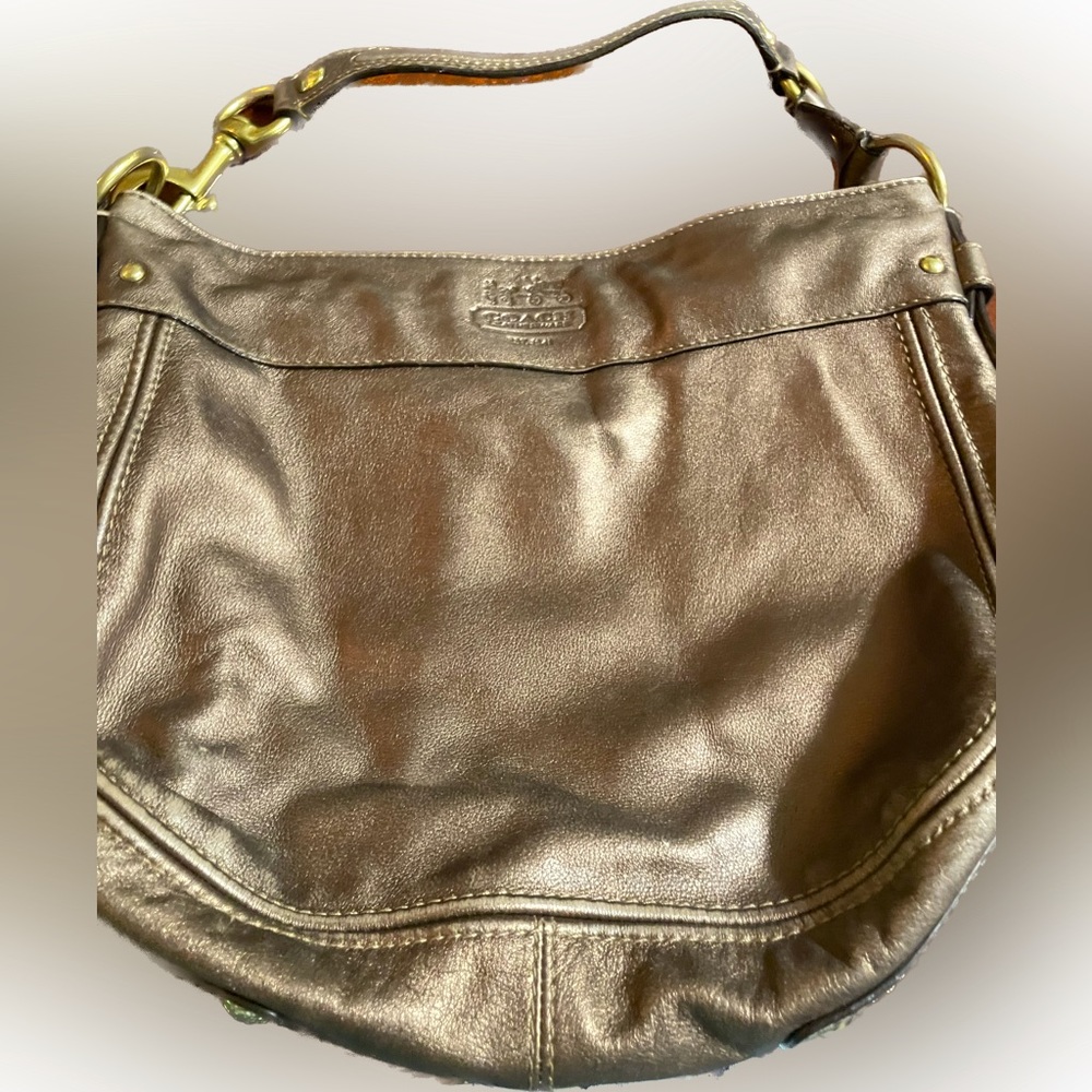 Used COACH shoulder bag. Has ink spots on inside of purse ROSE GOLD COLOR